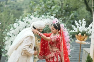 Bride and groom sharing a joyful wedding moment beneath a floral arch.