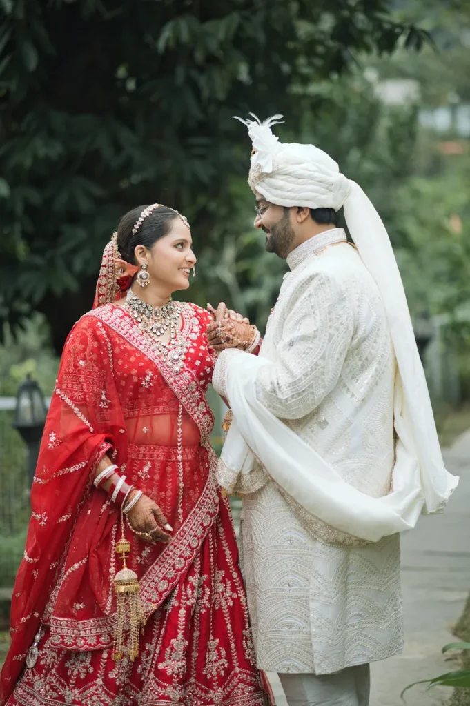 Bride and groom sharing a joyful moment while holding hands in traditional wedding attire.