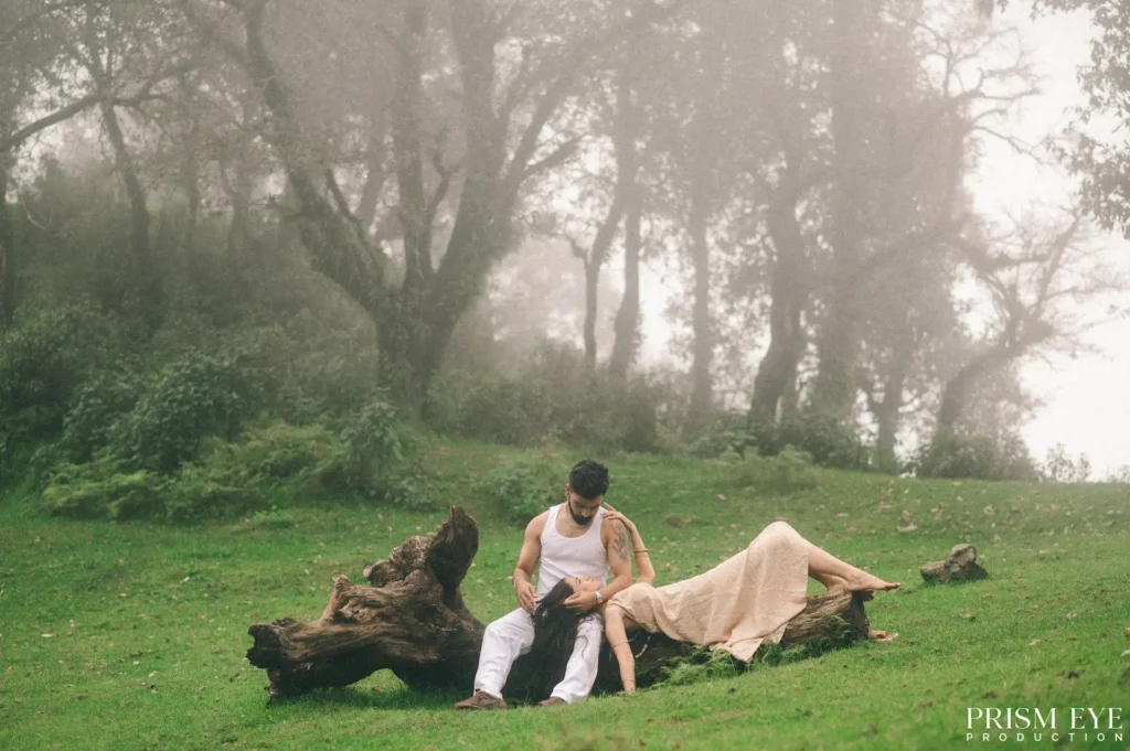 Couple enjoying a monsoon pre-wedding shoot in a misty open meadow surrounded by lush green forests in Uttarakhand.