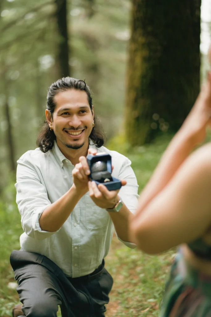 A man kneeling with an open ring box during a romantic proposal