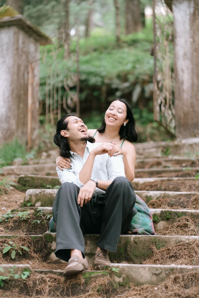 Proposal Photography in Mussoorie A couple laughing together while sitting on the steps in the woods