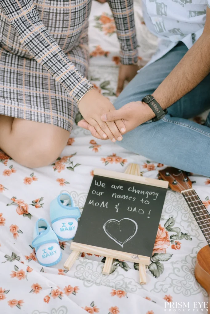 A little pair of shoes, a heartfelt announcement, and two excited hearts waiting to become parents. Maternity couple holding hands with baby shoes and a baby announcement sign