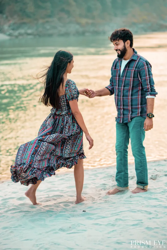 Couple holding hands during a romantic pre-wedding photoshoot on the sandy banks of the Ganga River in Rishikesh.