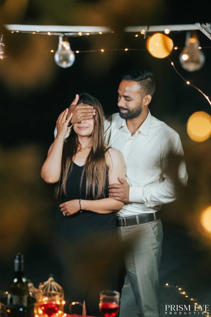 A couple sharing a romantic surprise moment under warm fairy lights during a proposal photoshoot in Rishikesh.