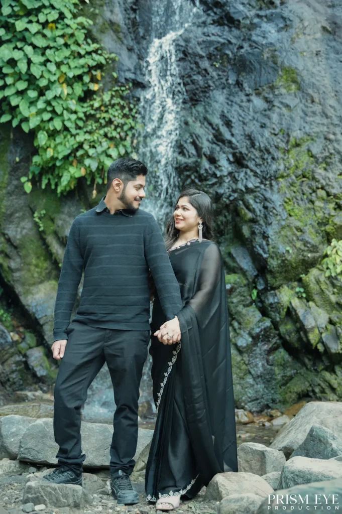 Couple holding hands during a romantic proposal photoshoot beside a waterfall in Rishikesh.