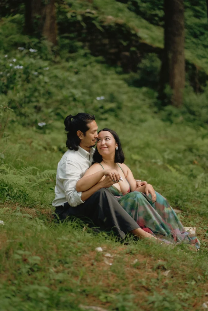 A couple sitting close together on a grassy hillside and enjoying a quiet moment