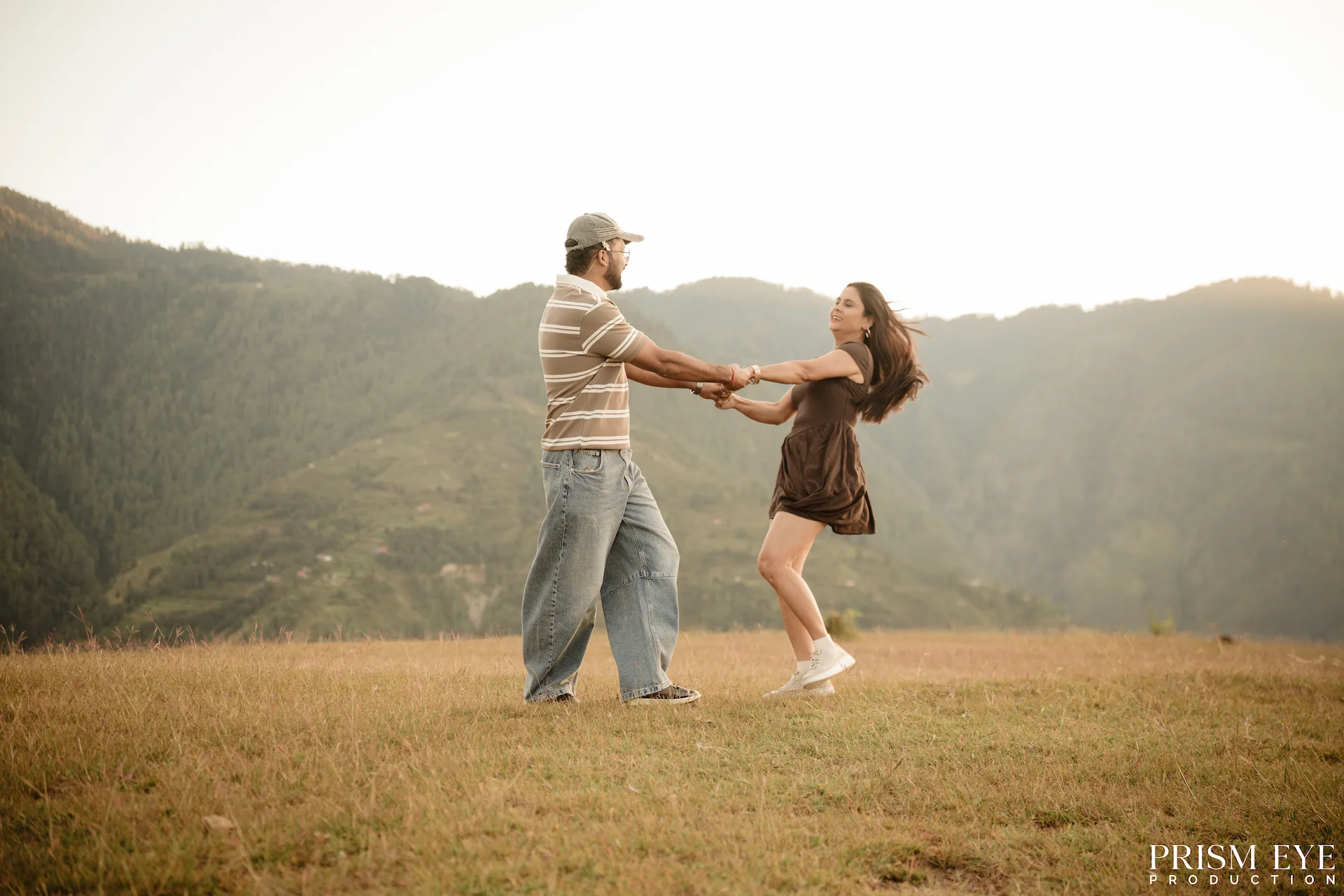 Couple twirling hand in hand in a golden meadow during a pre-wedding shoot in Chakrata, Uttarakhand