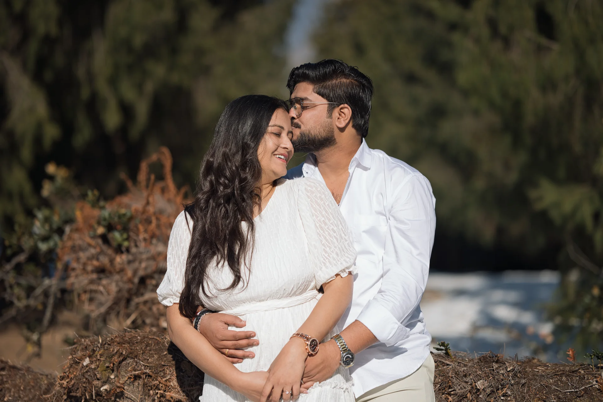 Couple in white outfits embracing with a forehead kiss at Dhanaulti Eco Park pre-wedding shoot