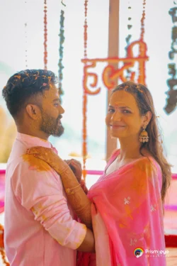 A cheerful Haldi ceremony portrait capturing genuine smiles, vibrant colors, and the excitement of celebrating love before the wedding. Couple sharing a joyful moment during their Haldi ceremony with turmeric and floral decorations in the background.