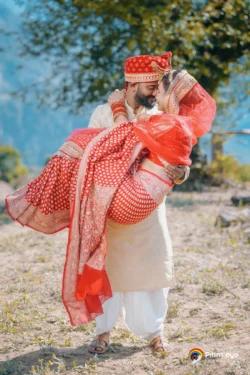 A joyful wedding portrait as the groom carries his bride, capturing love, laughter, and the beauty of their destination wedding in the mountains. Groom carrying the bride during a romantic destination wedding portrait with scenic mountain views in Uttarakhand.