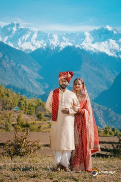 A timeless wedding portrait of the bride and groom surrounded by the breathtaking Himalayan landscape, celebrating love in the heart of Uttarakhand. Bride and groom posing with the Himalayan mountains during their destination wedding in Uttarakhand.
