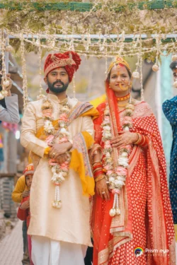 The bride and groom stand together after exchanging floral garlands, celebrating a joyful and timeless moment in their wedding ceremony. Bride and groom wearing floral garlands during their traditional Hindu wedding ceremony in Uttarakhand.