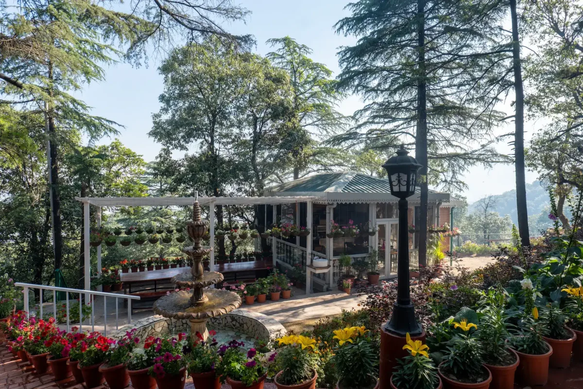 Peaceful garden courtyard in Mussoorie featuring colorful flowers, a fountain, and scenic Himalayan surroundings. Beautiful garden courtyard with flowers and a fountain at a luxury resort in Mussoorie, Uttarakhand