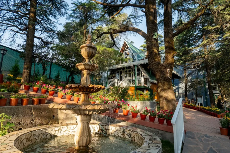 Scenic mountain home in Mussoorie featuring a landscaped garden, decorative fountain, and peaceful Himalayan surroundings. Heritage mountain home with garden fountain and pine trees in Mussoorie, Uttarakhand.
