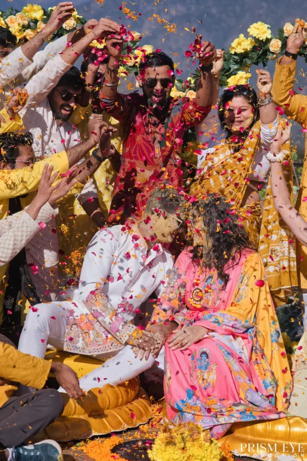 Bride and groom celebrating with friends as colorful flower petals fill the air
