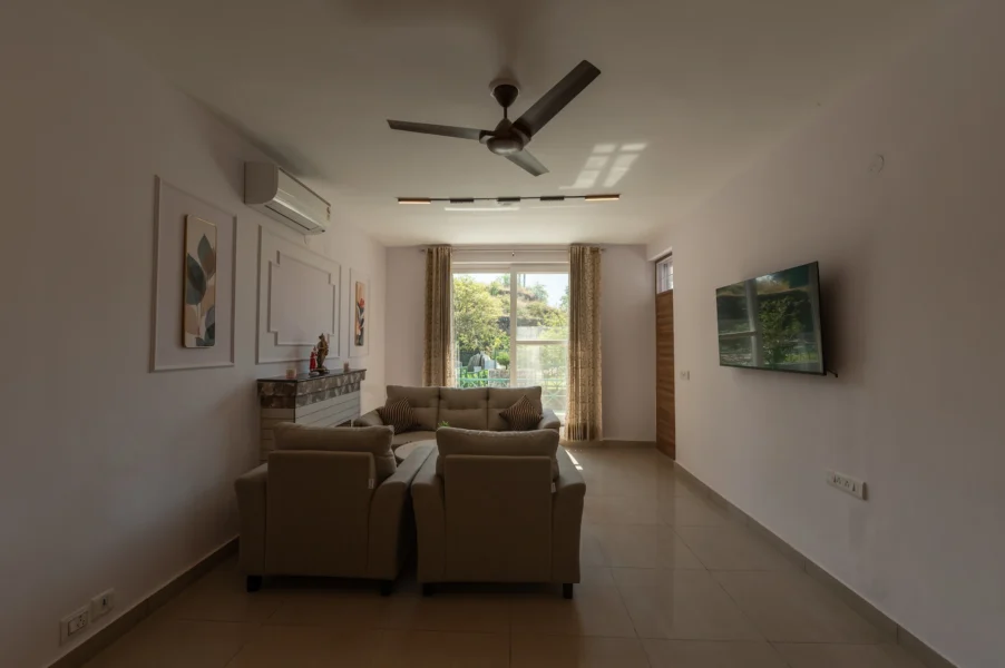 Spacious lounge area in a Mussoorie mountain retreat featuring modern interiors, comfortable seating, and natural light. Cozy modern lounge with large window and comfortable seating in a luxury Mussoorie retreat.