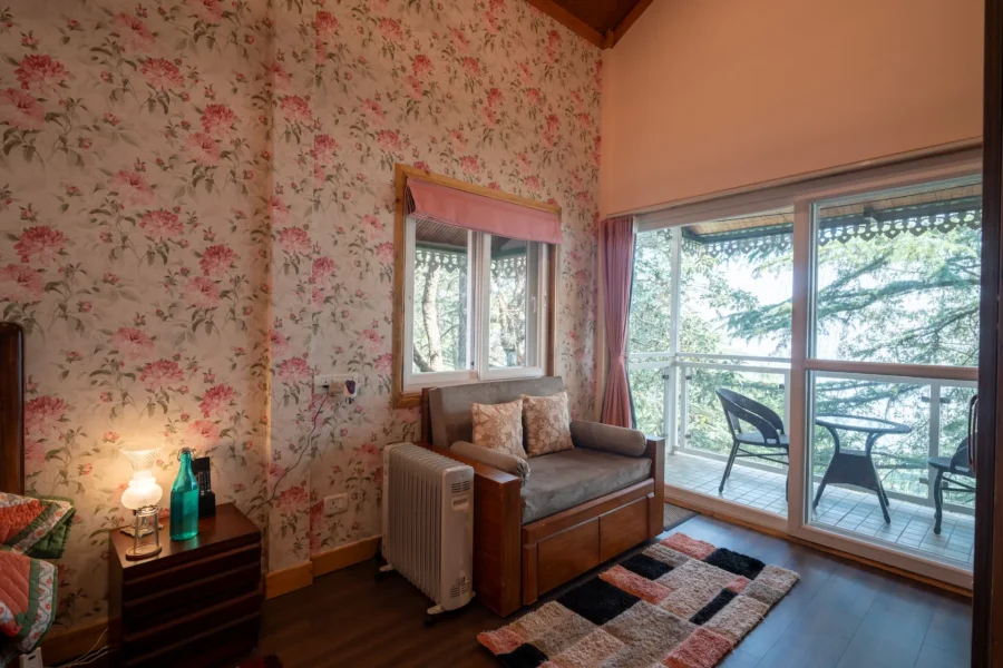 Peaceful balcony view bedroom in Landour, Mussoorie featuring cozy interiors, large windows, and beautiful forest surroundings. Cozy bedroom with private balcony and forest view in Landour, Mussoorie, Uttarakhand.
