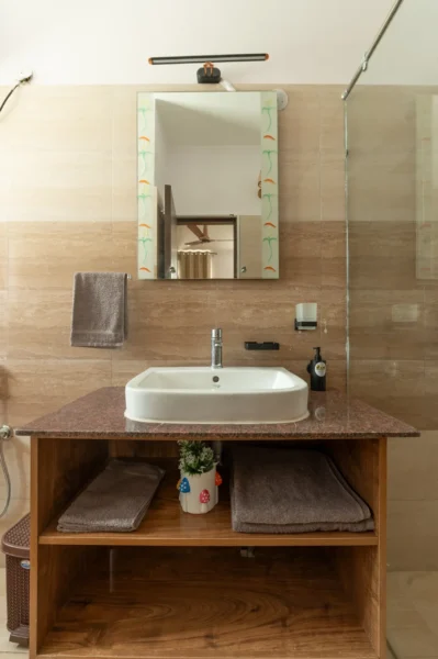 Elegant modern bathroom vanity in a Mussoorie luxury villa featuring a wooden cabinet, premium sink, and stylish contemporary design. Modern bathroom vanity with wooden cabinet and mirror in a luxury villa in Mussoorie, Uttarakhand.