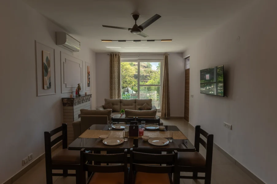 Elegant dining and living area in a premium villa in Jharipani, Mussoorie featuring modern interiors, comfortable seating, and scenic mountain surroundings. Premium villa dining and living area with mountain view in Jharipani, Mussoorie, Uttarakhand.