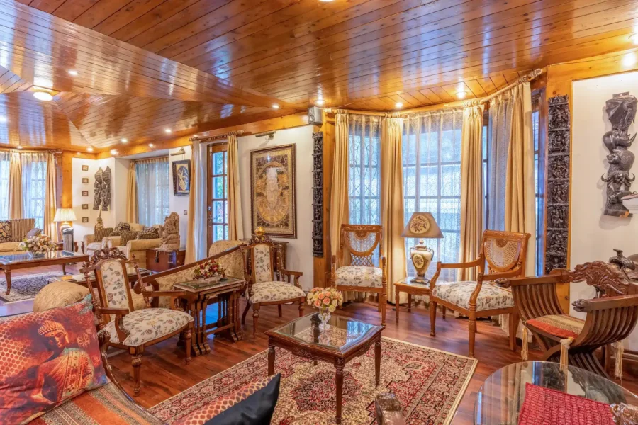 Beautiful wooden villa lounge area in Rishikesh featuring elegant furniture, warm wooden interiors, and a spacious luxury retreat ambiance. Real estate photography in Dehradun featuring a wooden villa lounge with large windows and seating area