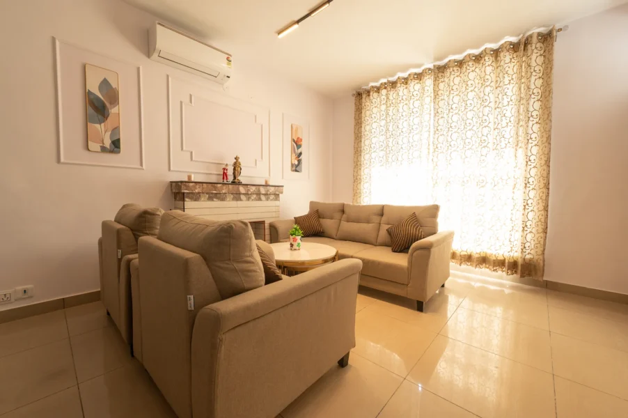 Bright and elegant living room in a Mussoorie luxury villa featuring comfortable sofas, natural light, and a relaxing mountain retreat atmosphere. Sunlit luxury villa living room with modern seating in Mussoorie, Uttarakhand.